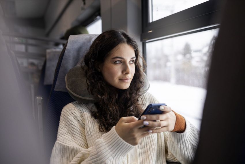 young woman using her smartphone while traveling by train